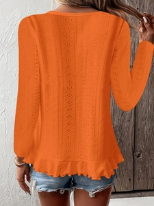 Détail du haut en tricot orange avec texture crochetée évidée et ourlet plissé ondulé