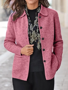 Detail der rosafarbenen Strickjacke mit Reverskragen und schwarzen Knöpfen auf der Vorderseite