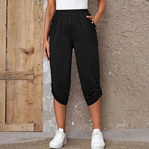 Detail of high waist elastic band and silver buttons on black women's capri pants