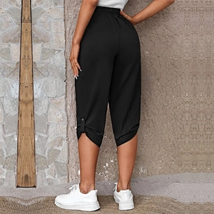 Detail view of black capri pants featuring an elastic high waist and side button accents