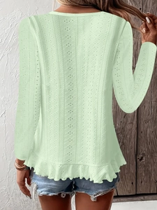 Détail d'un haut vert menthe à broderie anglaise avec manches longues et ourlet à volants