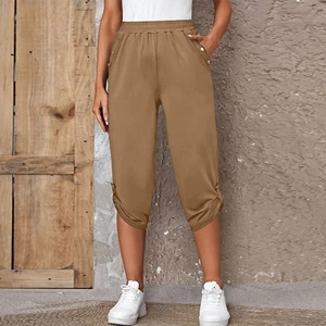 Detail of casual khaki cropped pants with elastic waist and metal decorative buttons
