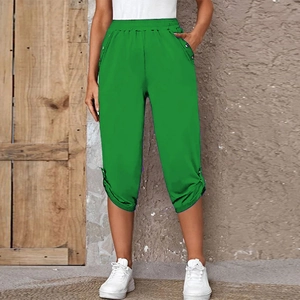 Detail of green high-waisted capri pants featuring elastic waist and buttoned side slits
