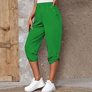 Detail of bright green cropped pants featuring high-waist elastic band and side buttons