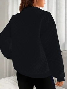 Close-up of black sweatshirt featuring textured diamond pattern and zipper detail