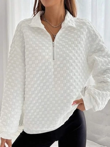 Detail of white sweatshirt featuring 3D checkered embossed texture and half-zip collar