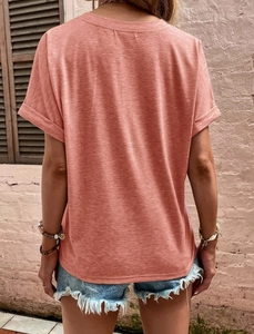 Close-up of rolled sleeves and textured coral pink fabric on a women's short sleeve T-shirt