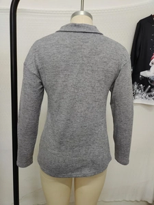 Detail view of the back side of a gray textured long sleeve knit top with zipper collar