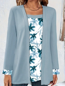 Close-up of light blue ribbed cardigan over white floral print inner top with folded cuffs