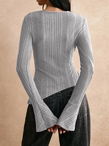 Detail of grey ribbed knit long sleeve top featuring flared sleeves and asymmetric hem