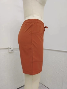 Detail of high waist linen shorts in rust red showing the drawstring and cargo side pocket