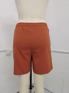 Detail view of elastic waistband and back pocket on rusty orange linen casual shorts