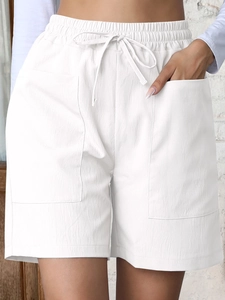 Detail of white linen shorts showing elastic drawstring waist and large cargo pockets