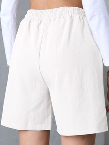 Detail view of the high-waisted white linen shorts with elastic waistband from the back