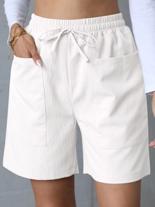 Detail of white linen shorts featuring elastic drawstring waist and large utility pockets