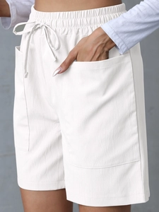 Detail of white linen shorts showing elastic drawstring waist and large side patch pockets