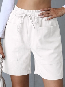 Detail view of white high waist white linen shorts with elastic drawstring and large front pockets