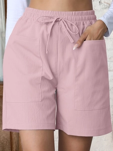 Detail of light pink linen shorts featuring elastic drawstring waist and large front pockets