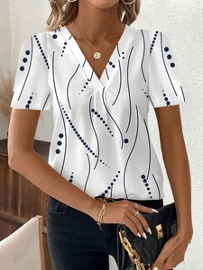 Dettaglio dello scollo a V con pieghe su un top bianco a maniche corte con stampe blu astratte