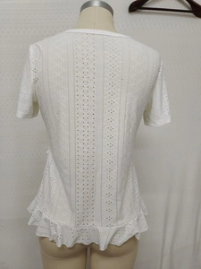 Detail of white cotton lace top featuring geometric embroidery and peplum back hem