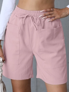 Detail of pink linen shorts featuring elastic drawstring waist and large front pockets