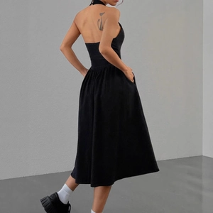 Détail d'une robe midi noire dos nu à licou avec une jupe plissée élégante