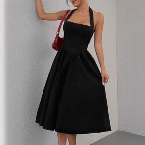 Détail d'une élégante robe dos nu noire avec taille cintrée et jupe évasée à plis