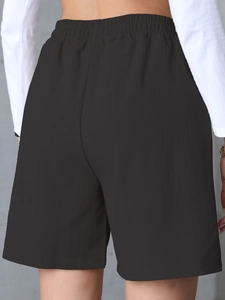 Detail view of the elastic high waist and back fit on black loose casual linen shorts