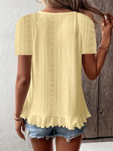 Detail of light yellow short sleeve top with eyelet embroidery and ruffle hem design