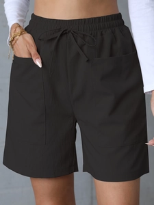 Detail of high-waist black linen shorts featuring elastic waistband and functional pockets