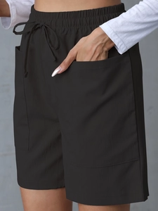 Detail of black loose linen shorts featuring elastic waist, drawstrings and large side pockets