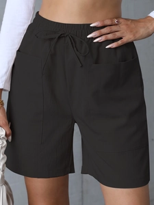Detail of high-waist linen shorts featuring a drawstring elastic waist and large side pockets
