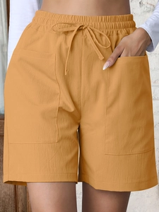 Close-up of mustard yellow linen shorts featuring a drawstring waist and cargo pockets