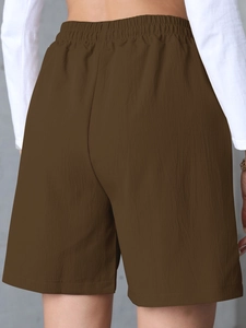 Detail view of high waist elastic waistband and wrinkled texture on brown linen shorts