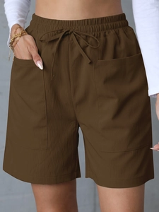 Detail of dark brown linen shorts featuring elastic drawstring waist and large side pockets