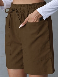Detail view of high-waisted linen shorts featuring elastic drawstring waist and large pockets