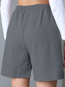 Detail view of high-waist dark grey linen shorts showing elastic waistband and crinkled texture