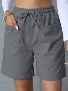 Detail of dark grey linen shorts showing elastic waistband, drawstring, and large square pockets