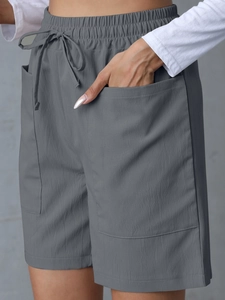Detail of high waist linen shorts featuring elastic drawstring waist and large patch pockets