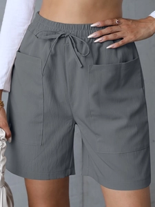 Detail of high-waisted linen shorts featuring textured grey fabric and adjustable drawstring