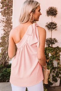 Detail view of pink one-shoulder top featuring a delicate shoulder bow tie design