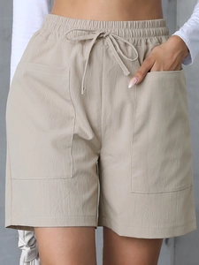Detail of high-waist linen shorts featuring elastic drawstring waist and large side pockets