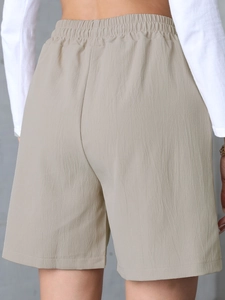 Detailed view of elastic high waist and textured fabric on beige linen casual shorts