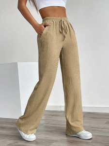 Detail view of khaki wide-leg trousers with vertical textured fabric and drawstring waist