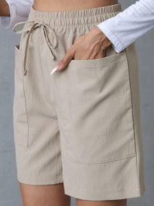 Detail of high-waisted linen shorts featuring an elastic waistband and drawstring