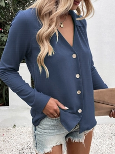 Detail of dark blue V-neck blouse with elegant wooden buttons and long sleeves
