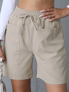 Detailed view of elastic drawstring waist and large pockets on beige linen casual shorts