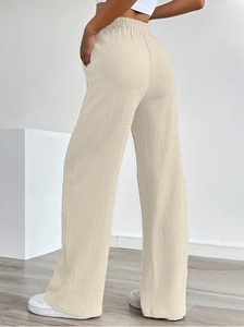 Detail of beige high waist wide leg trousers with pleated texture and side pockets