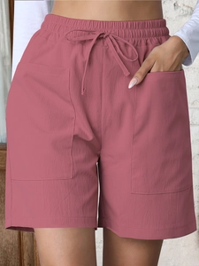 Detail of high-waisted linen shorts with elastic drawstring waist and large patch pockets