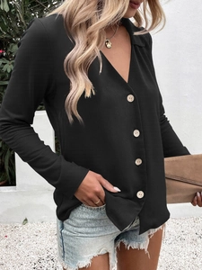 Detail of elegant black V-neck shirt featuring wood-grain buttons and smooth fabric texture